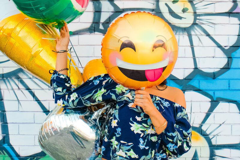 Happy woman hiding her face behind a balloon