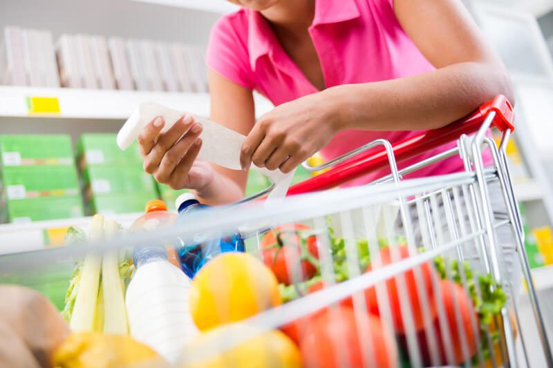 Woman with shopping trolley and receipt in supermarket